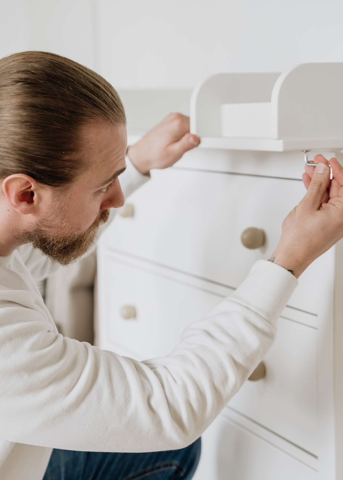 Ein Mann befestigt den Wickelaufsatz an eine IKEA Hemnes Kommode