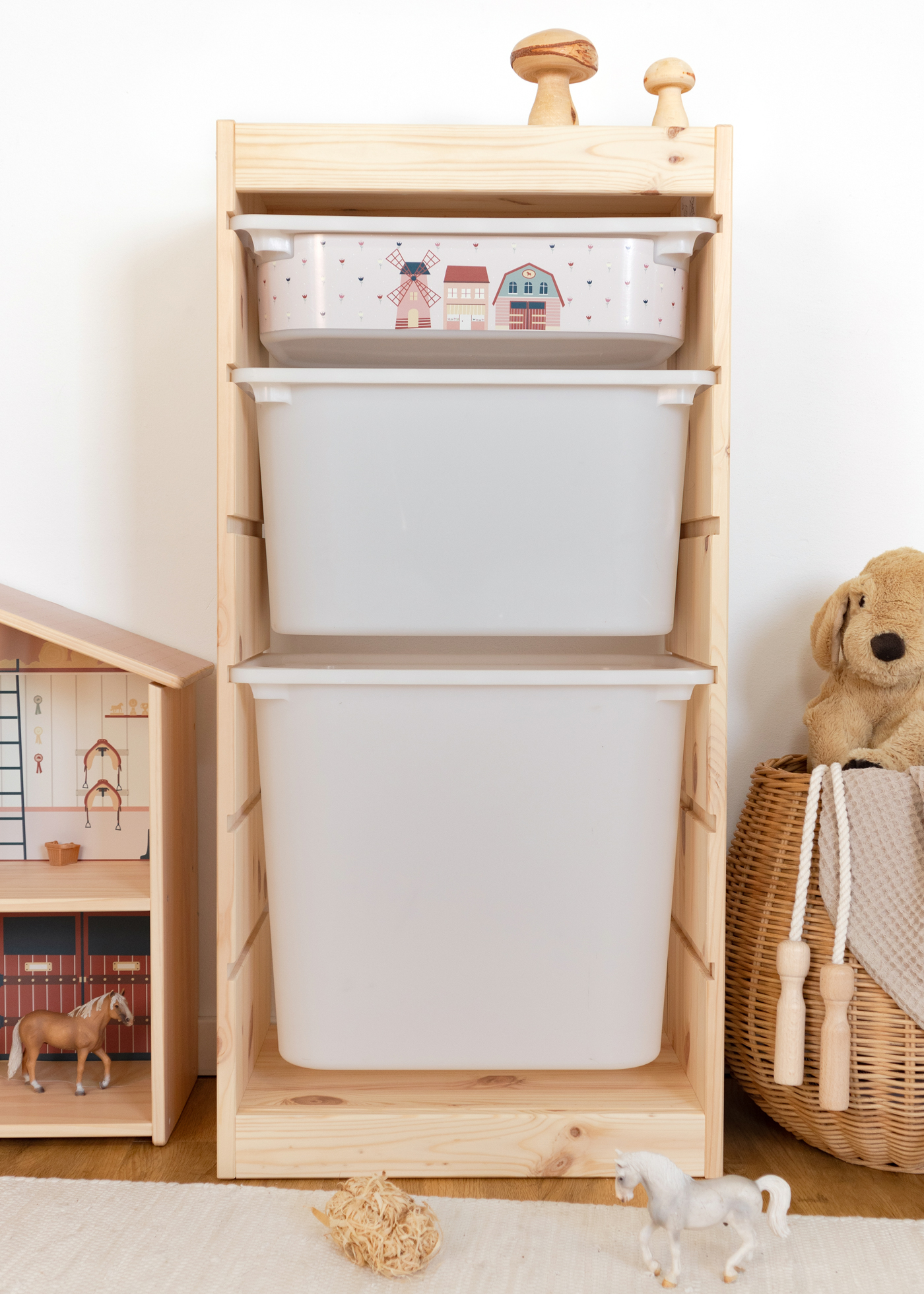 Aufbewahrungslösung mit Dorf-Motiv im IKEA Regal IKEA TROFAST Regal mit rosa Aufbewahrungsbox, bedruckt mit einer idyllischen Dorfszene, ideal für Kinderzimmer.