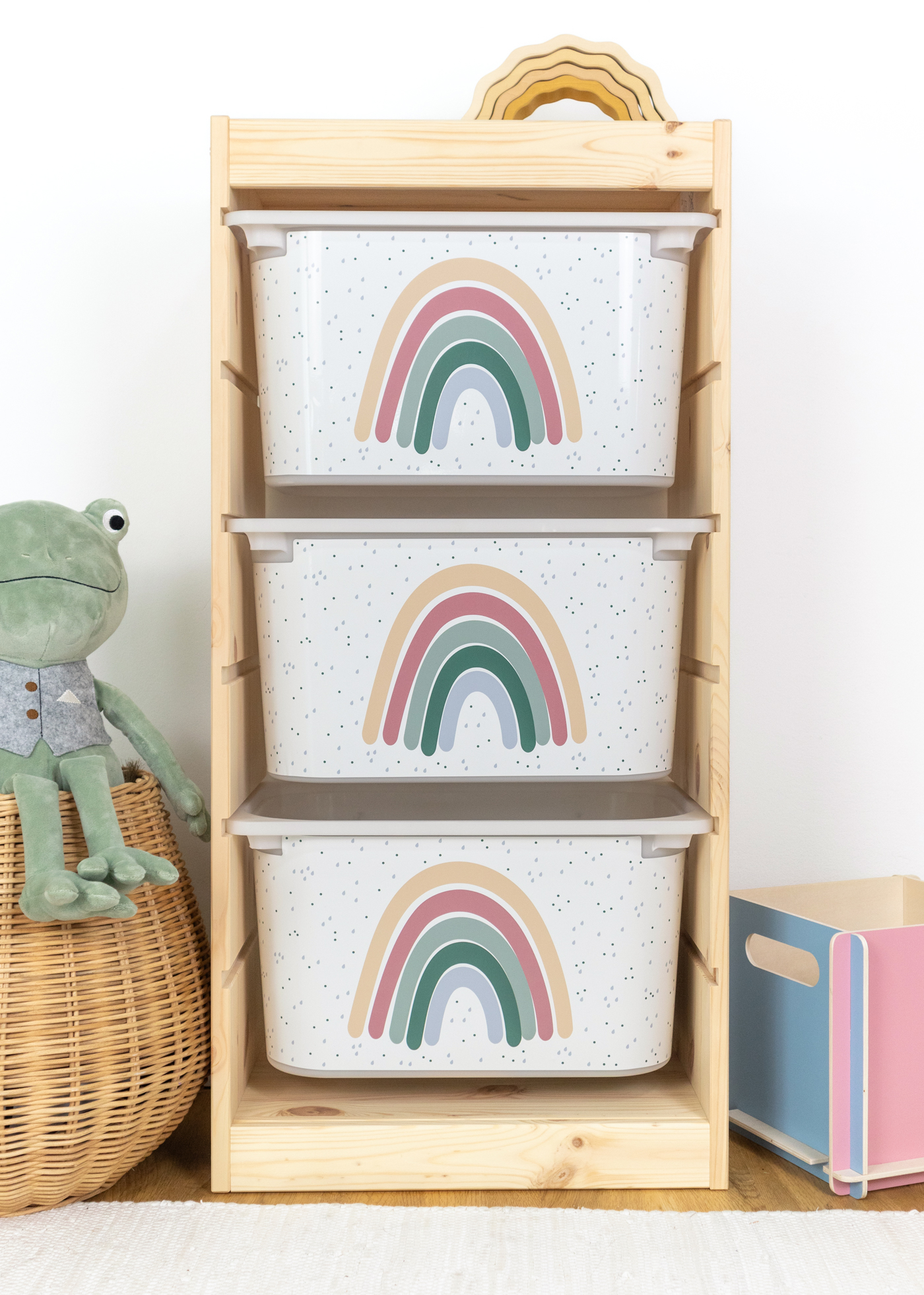 Kinder-Aufbewahrungsbox im TROFAST Regal mit Regenbogen Beige Box im IKEA TROFAST Regal mit kindgerechtem Regenbogen-Design.