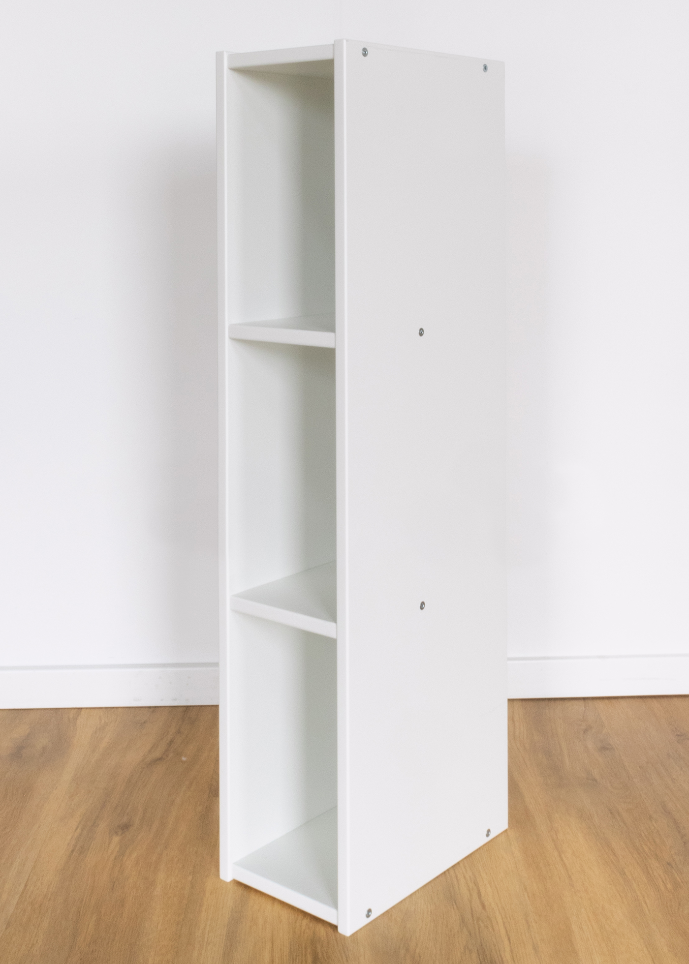 Rückwandregal zum Wickelaufsatz Ein dünnes weißes Regal steht hochkant in einem Raum