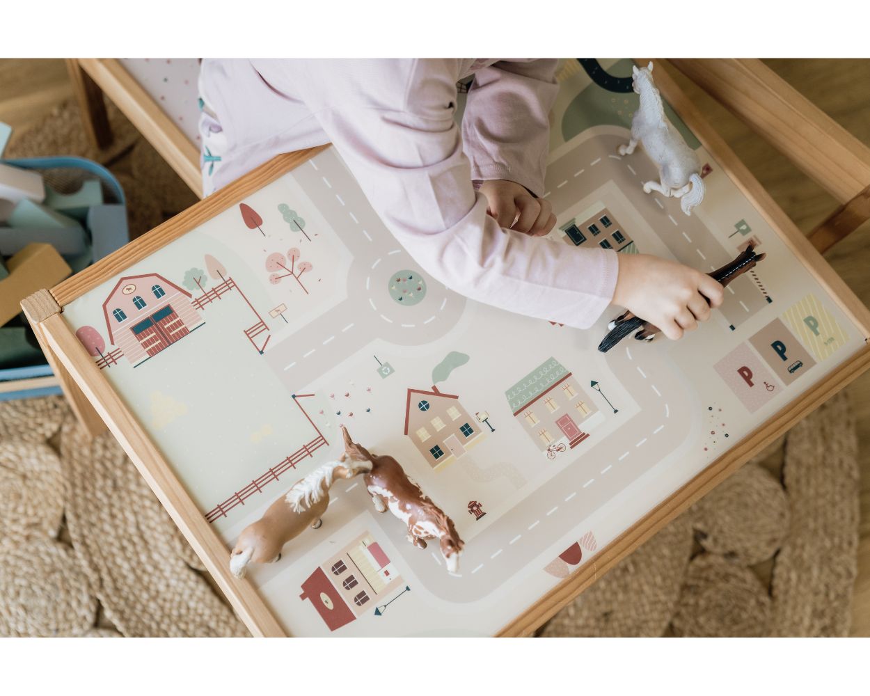 Kindertisch mit Klebefolie Mädchen spielt mit Spielzeugpferden auf ihrem Kindertisch mit Limmaland-Klebefolie