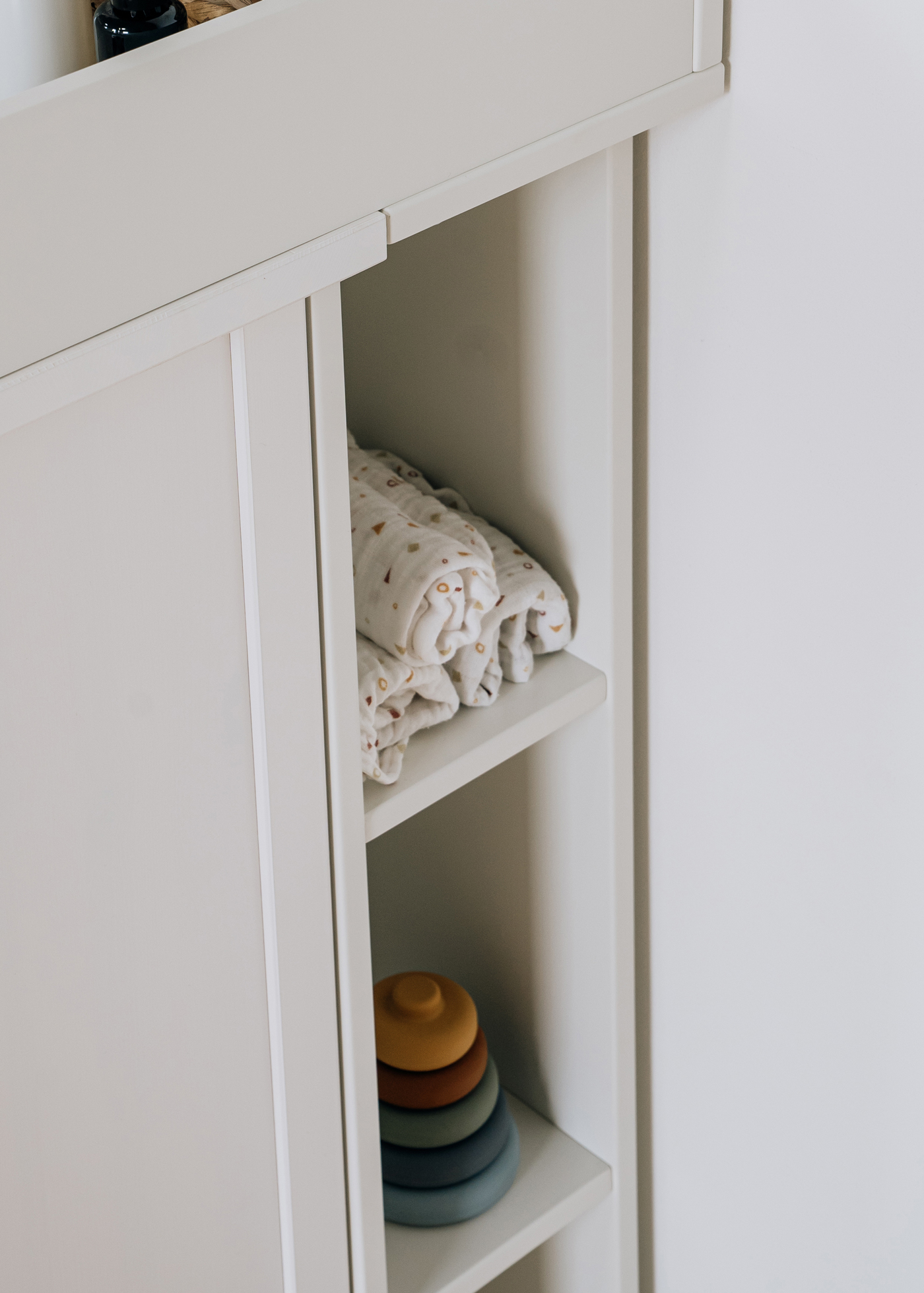 Wickelaufsatz mit Regal Ein weißes hochkantiges Regal ist mit Wickelutensilien befüllt