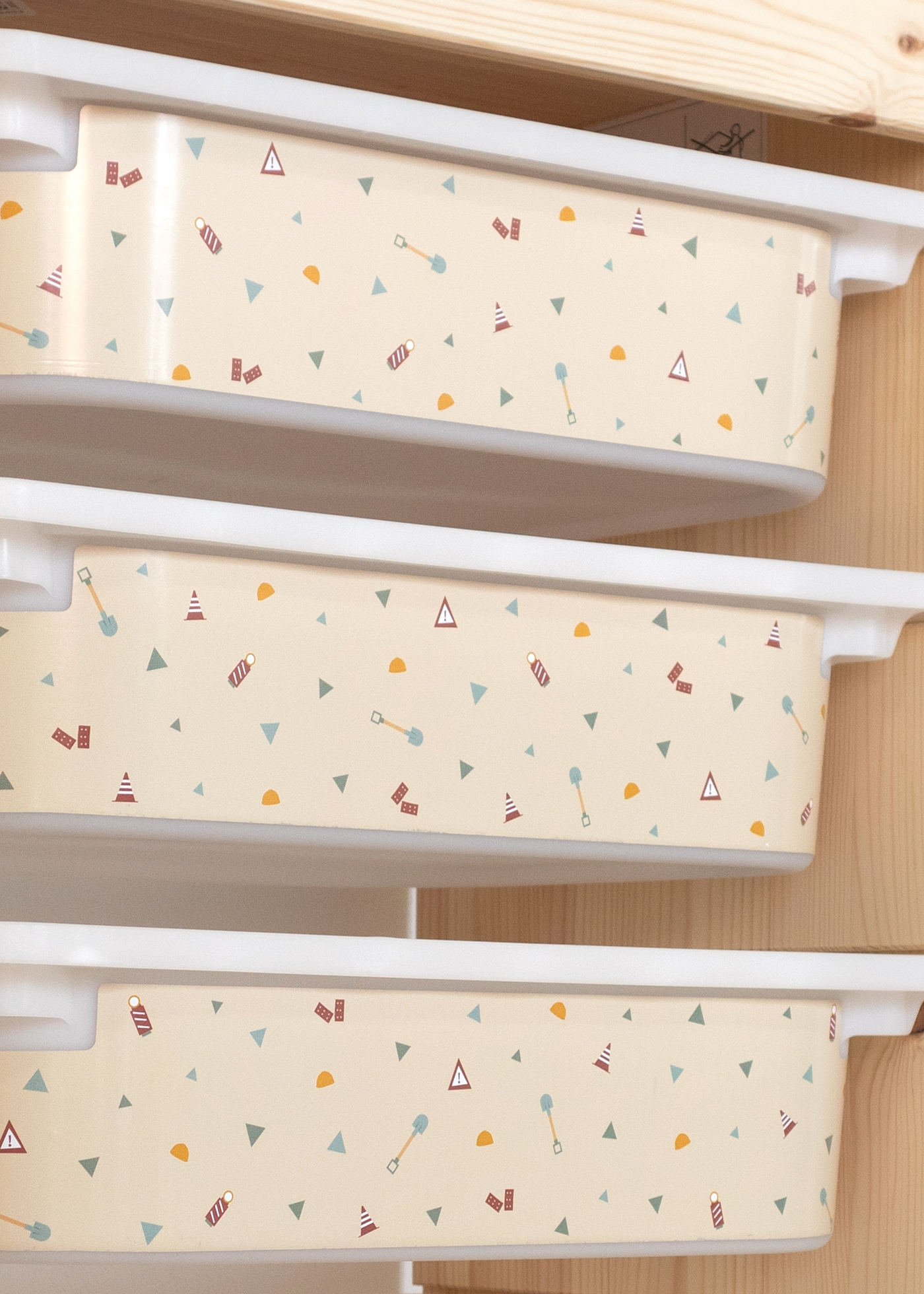 Aufbewahrungsbox im IKEA TROFAST Regal, dekoriert mit Baustellen-Motiven wie Bagger, Kran und Kipplader.