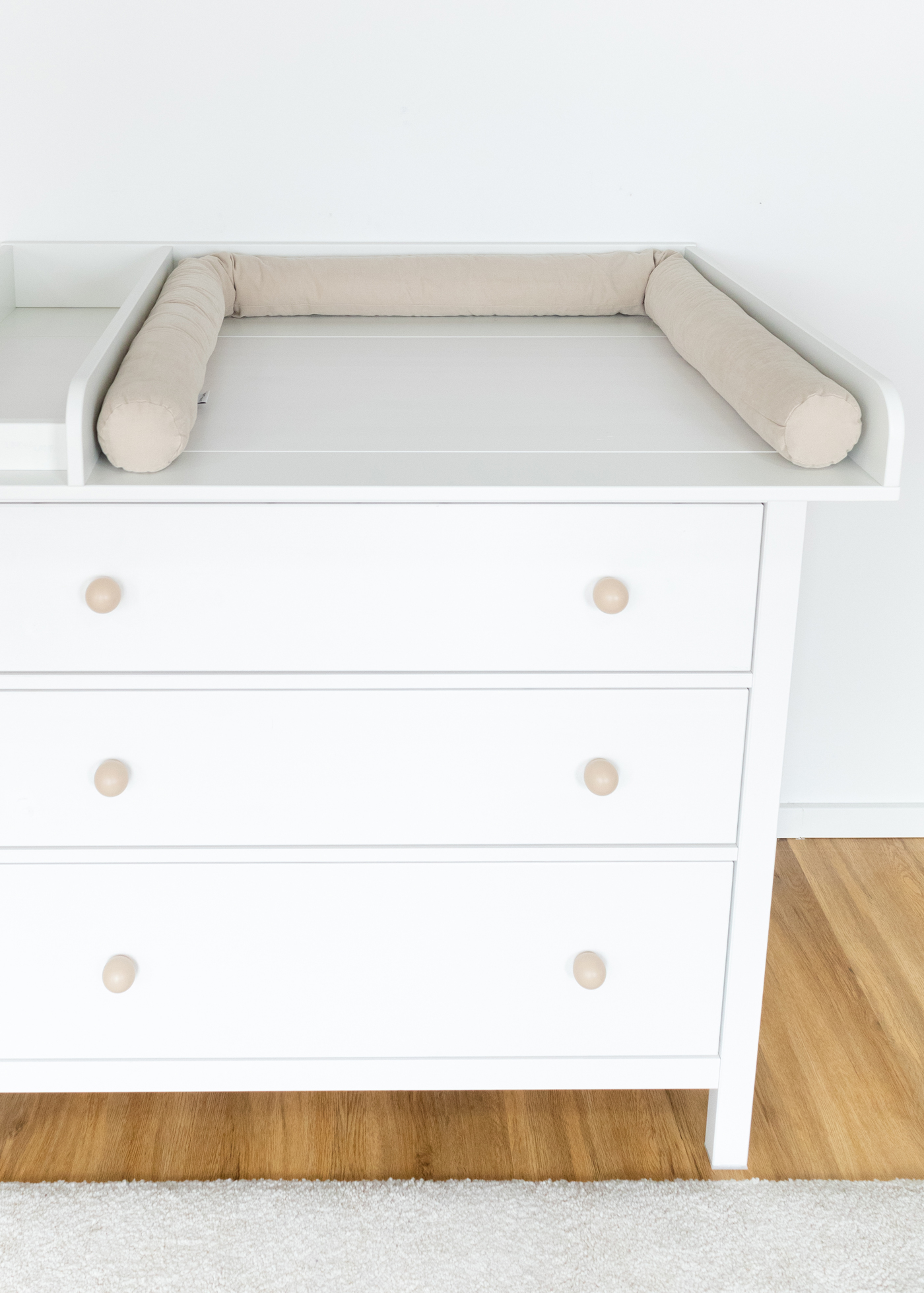 Eine beige Wickelauflage liegt auf der weißen IKEA HEMNES Kommode